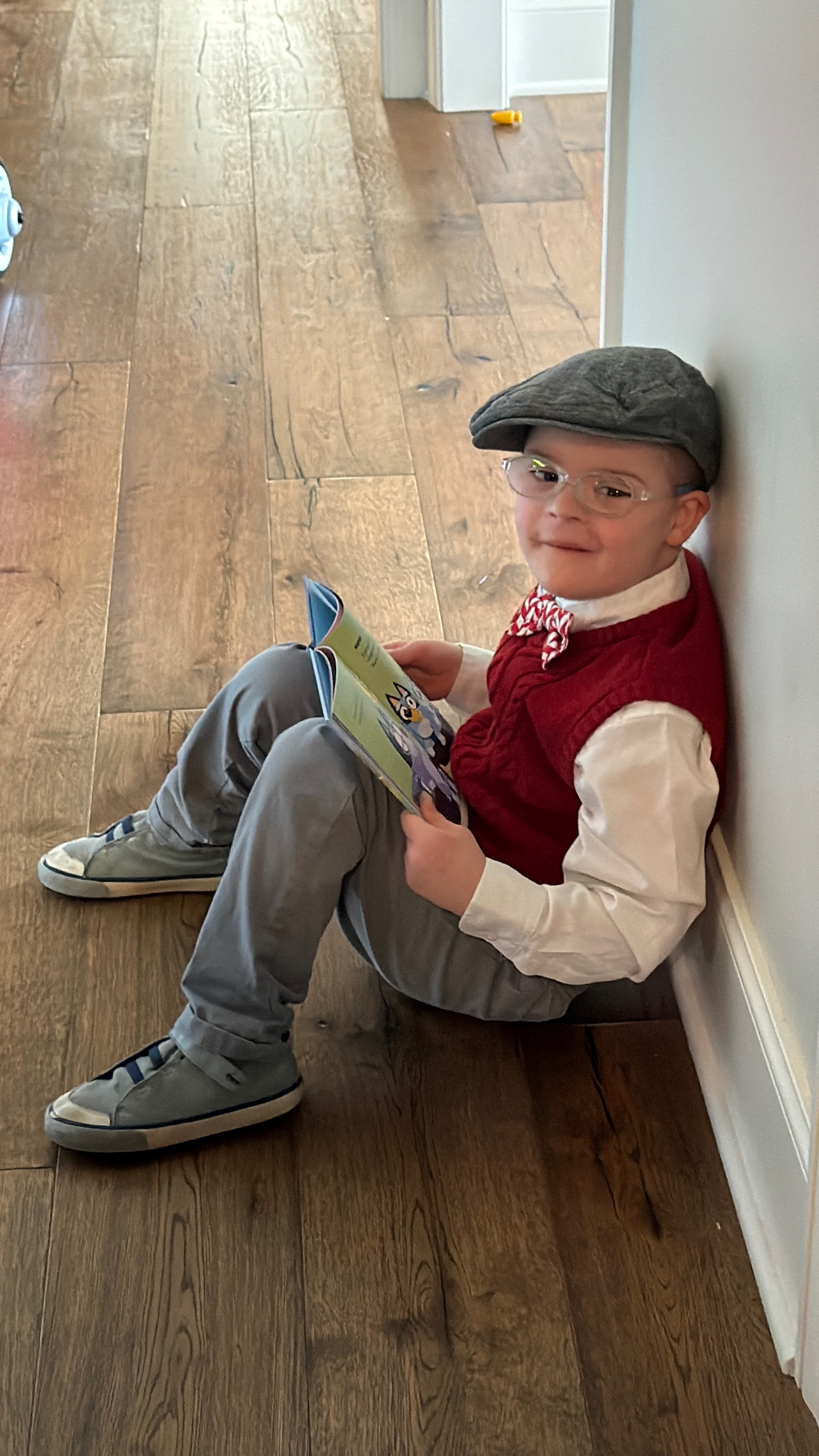 Charlie reading a book in a dapper outfit with a newsboy cap